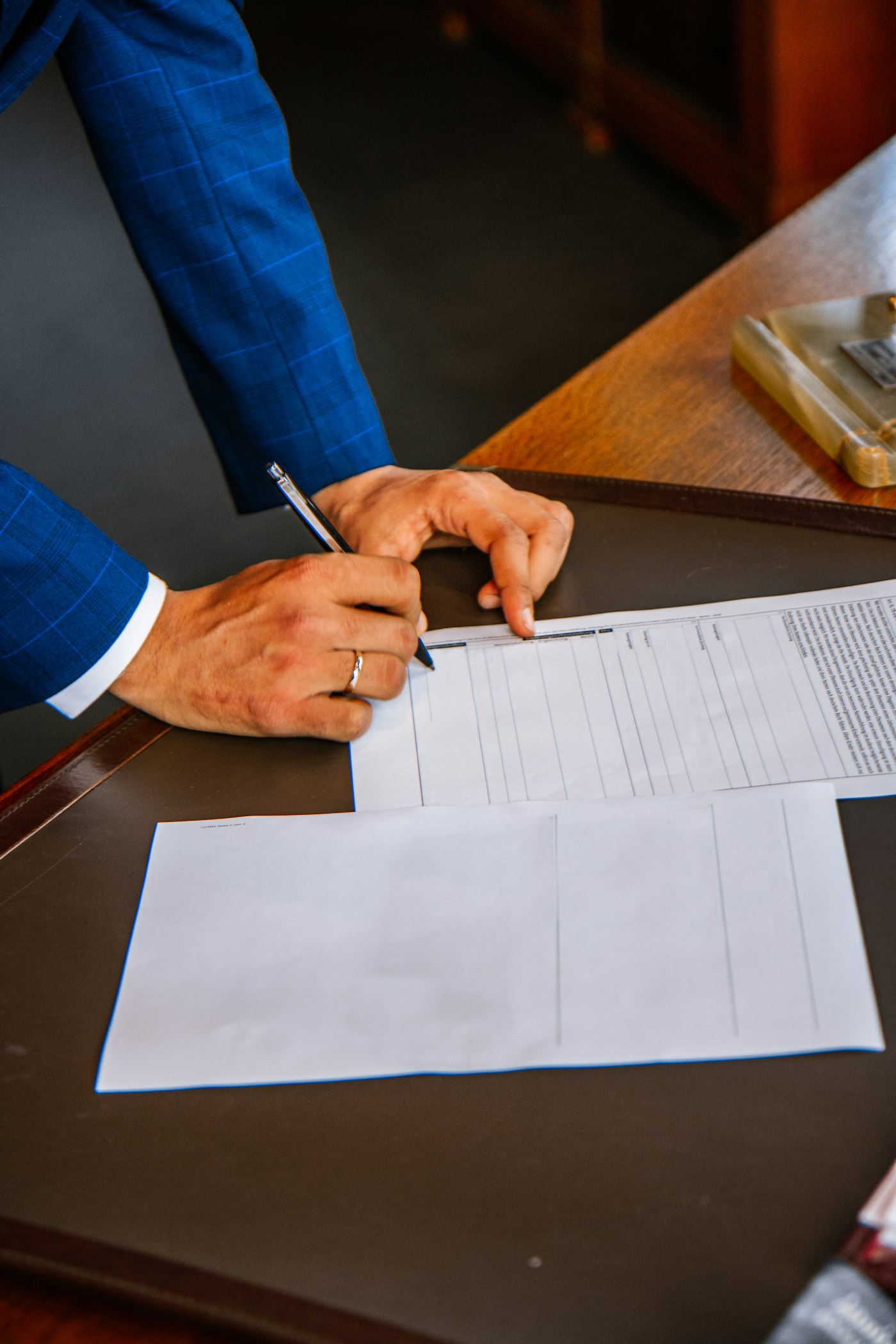 Person signing a paper document at a desk